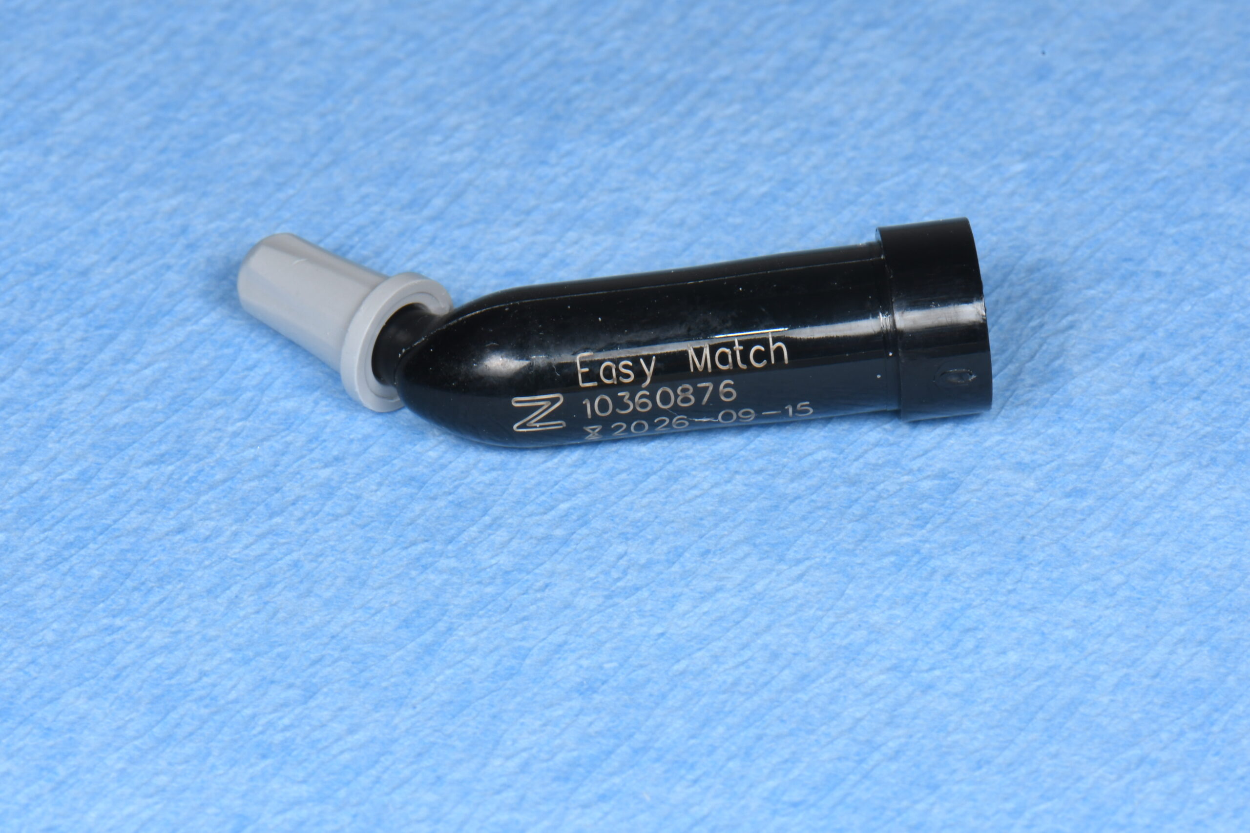 Black plastic device labeled 'Easy Match' with a gray nozzle on a blue surface